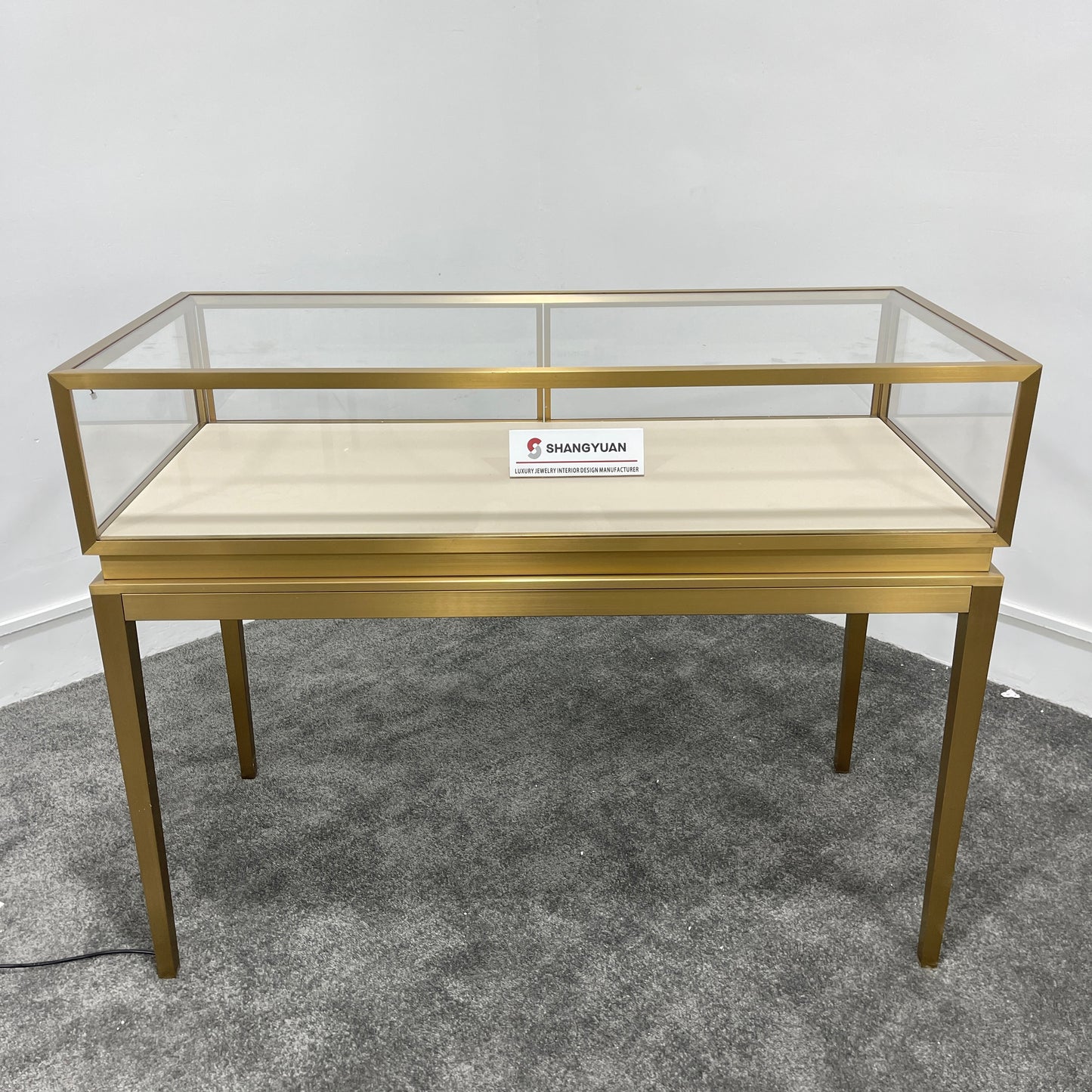 Full front view of gold stainless steel jewelry showcase with dual sliding glass doors and lock for jewelry store