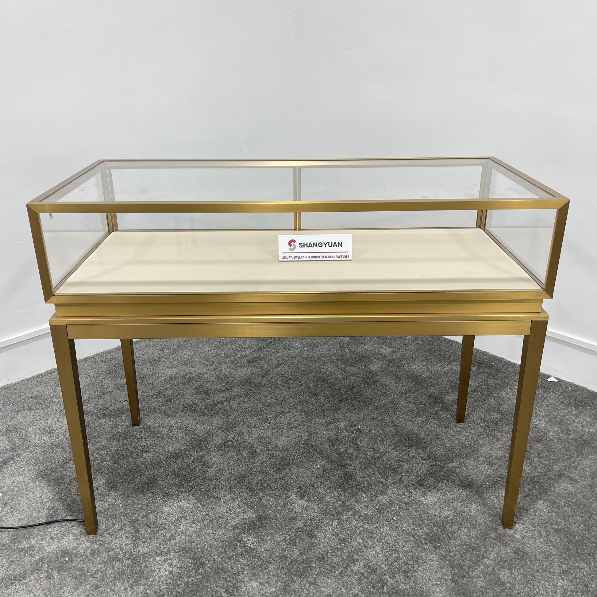 Full front view of gold stainless steel jewelry showcase with dual sliding glass doors and lock for jewelry store