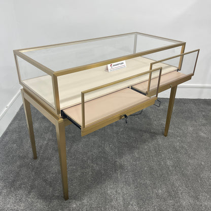 Gold jewelry display case with sliding glass door open showing lockable drawer and storage shelf underneath